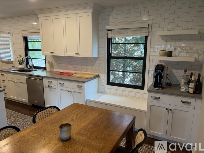 A kitchen with white cabinets and a wooden table.