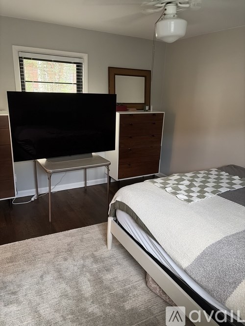 A bedroom with a bed, a television, and a window.