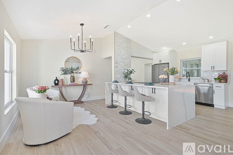 A modern kitchen with a white theme and a dining area with a round table and chairs.