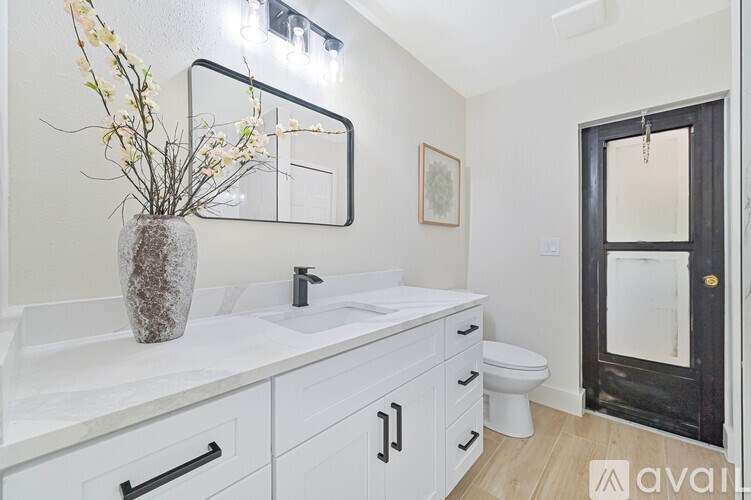 A bathroom with a white counter top and a vase with flowers on it.