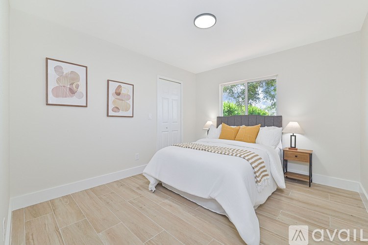 A bedroom with a large bed and two framed pictures on the wall.
