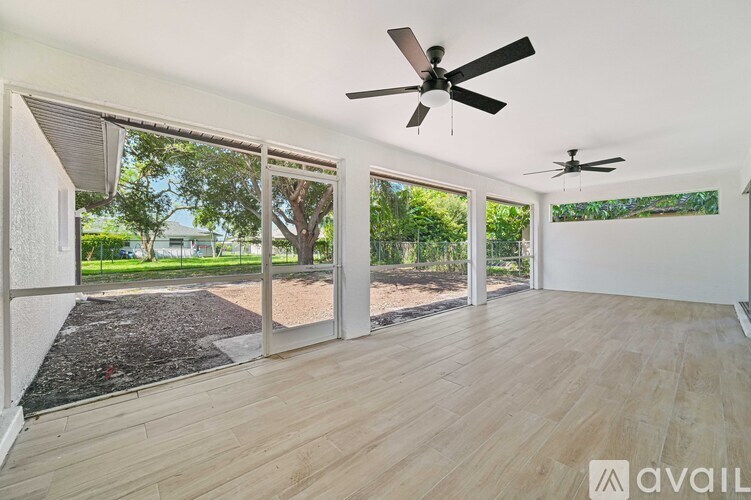A room with a ceiling fan and sliding glass doors leading to a backyard.