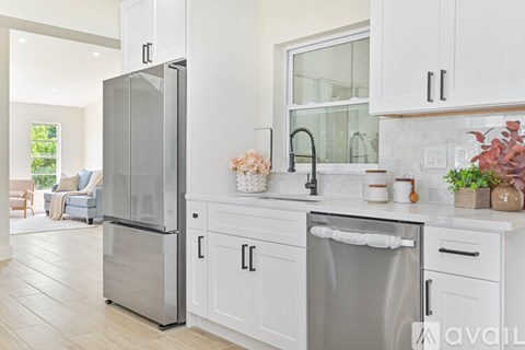 A modern kitchen with a stainless steel refrigerator and white cabinets.
