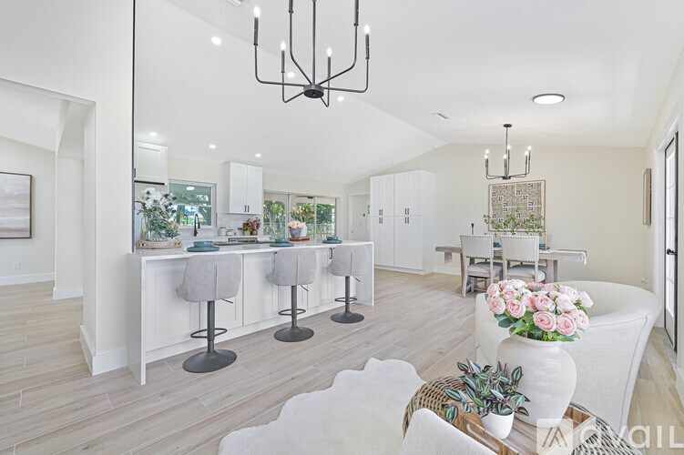 A modern living room with a dining area and a kitchen in the background.