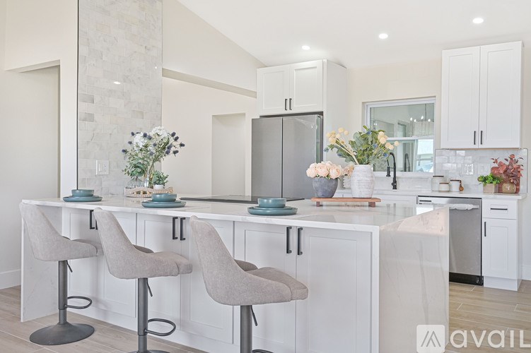 A kitchen with white cabinets and a marble backsplash.