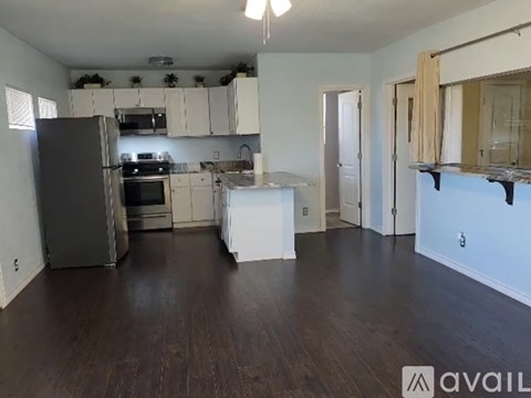 A kitchen with white cabinets and a black fridge.