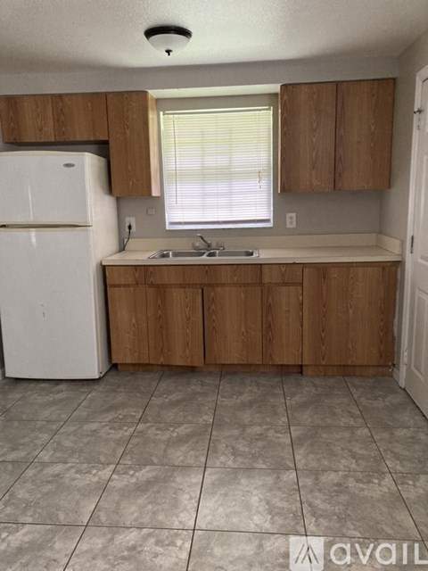 A kitchen with a white refrigerator and wooden cabinets.