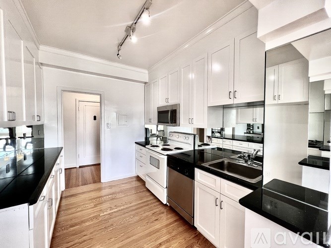 A kitchen with white cabinets and black countertops.