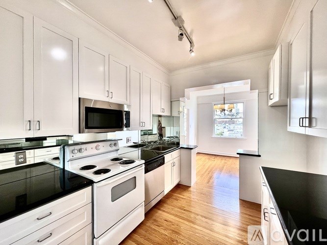A kitchen with white cabinets and black countertops.