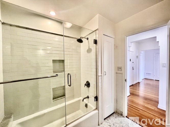 A white bathroom with a glass shower stall and a white door.