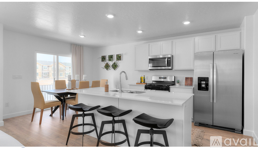 A kitchen with white cabinets and a white countertop with a refrigerator, microwave, and stove.