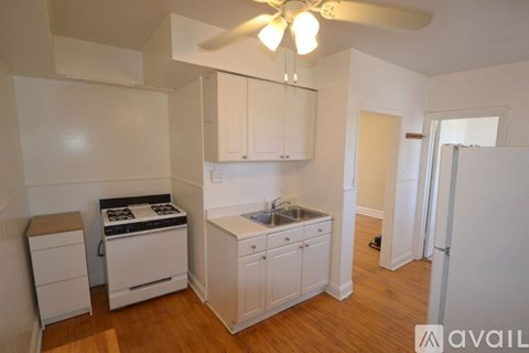 A kitchen with white cabinets and a wooden floor.