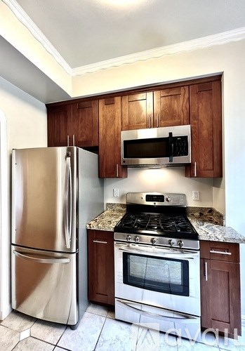 A kitchen with a stainless steel refrigerator, microwave, and oven.