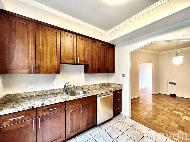 A kitchen with brown cabinets and a marble countertop.