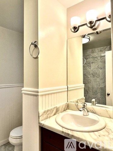 A bathroom with a toilet, sink, and mirror.