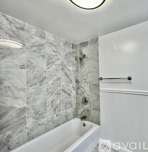 A white bathtub with a marble tile wall.