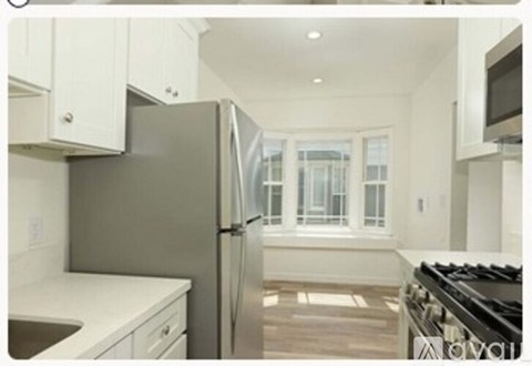 A modern kitchen with a stainless steel refrigerator and white cabinets.