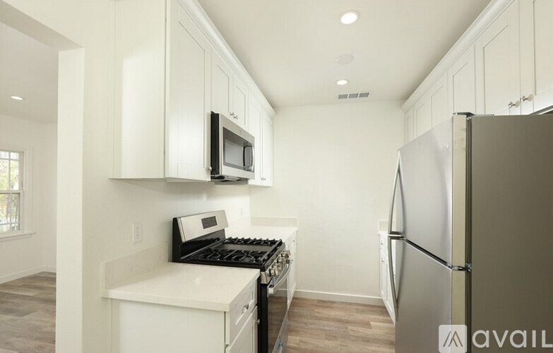 A kitchen with white cabinets and a stainless steel refrigerator.