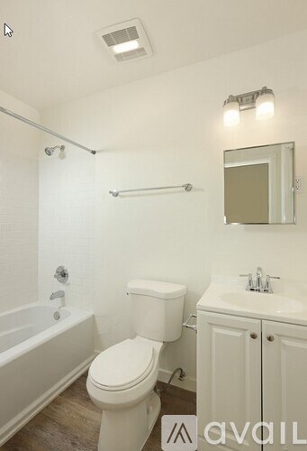 A white toilet is in a bathroom with a white tub and sink.
