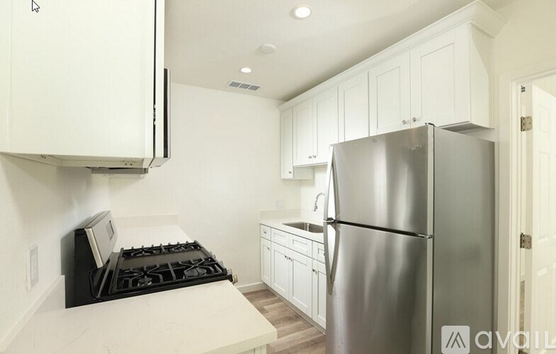 A kitchen with a stove, refrigerator, and cabinets.