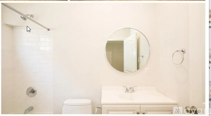 A white bathroom with a round mirror and a toilet.