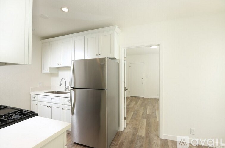 A kitchen with a stainless steel refrigerator and white cabinets.