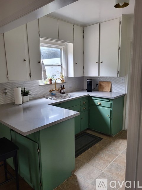 A kitchen with green cabinets and a white countertop.