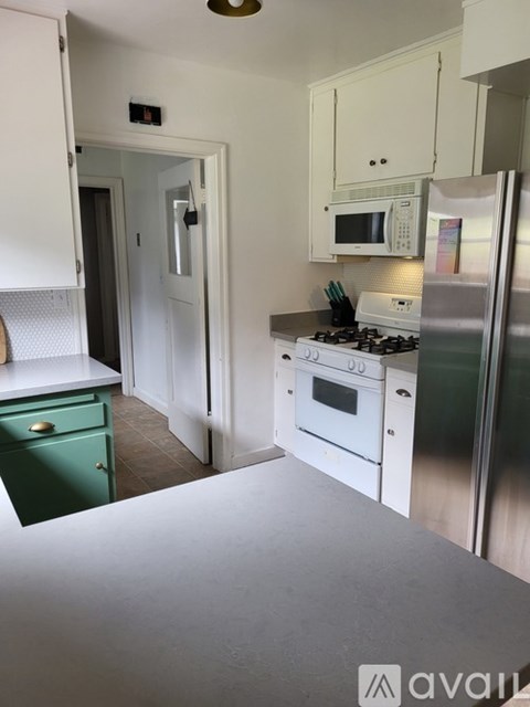 A kitchen with white cabinets and a green drawer.
