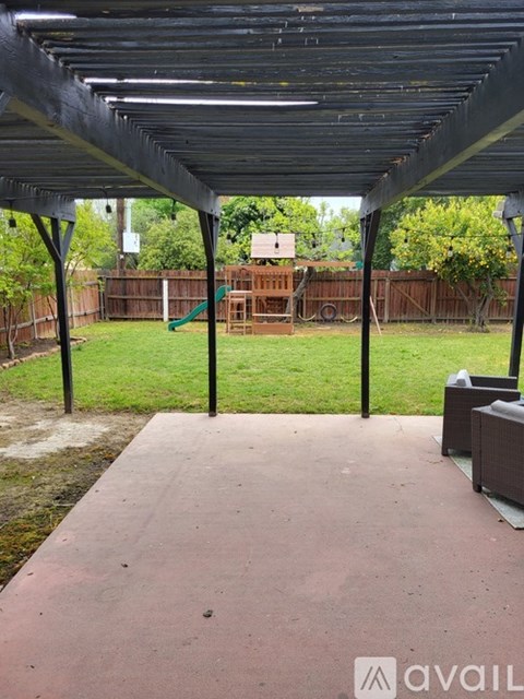A patio with a black roof and a green lawn in the background.