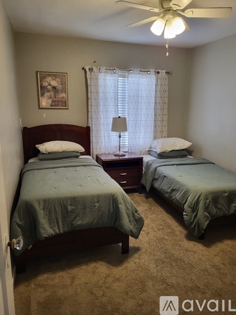 Two beds in a room with a ceiling fan.
