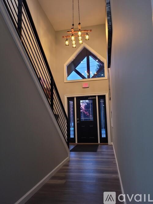 A hallway with a chandelier and a window with a view of the night sky.