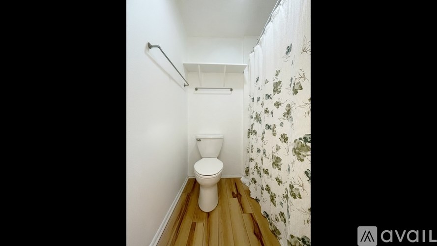 A white toilet in a small bathroom with floral wallpaper.