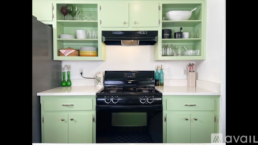 A kitchen with green cabinets and a black stove top.