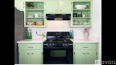 A kitchen with green cabinets and a black stove top.
