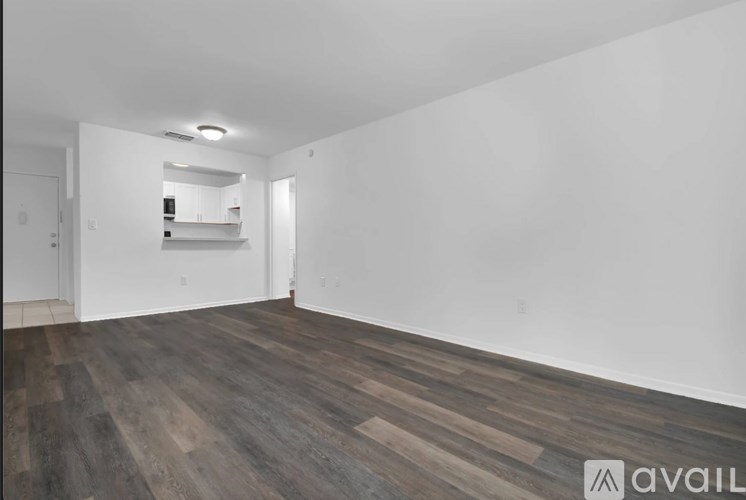 A spacious room with wooden flooring and white walls.