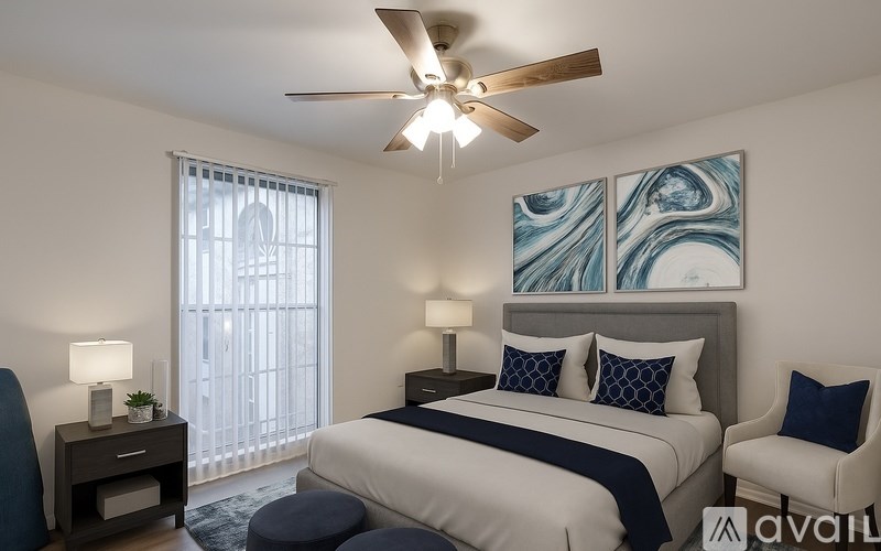A bedroom with a bed, chair, and ceiling fan.