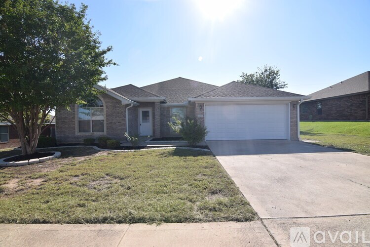 A house with a driveway and a tree in front of it.