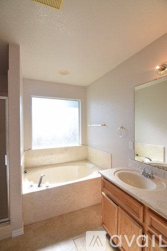 A bathroom with a tub, sink, and mirror.