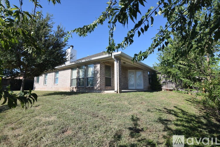 A house with a well-kept lawn and trees in the foreground.