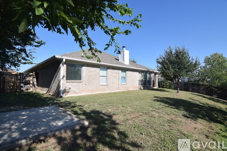 A house with a blue door and a white window is surrounded by a grassy yard.
