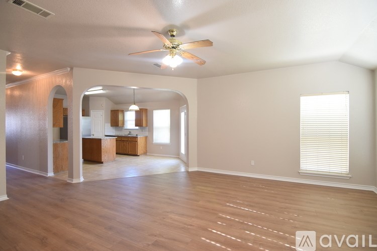 A spacious living room with a ceiling fan and hardwood floors.