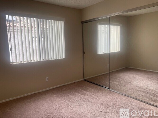 A room with a carpeted floor, a sliding glass door, and a window with blinds.