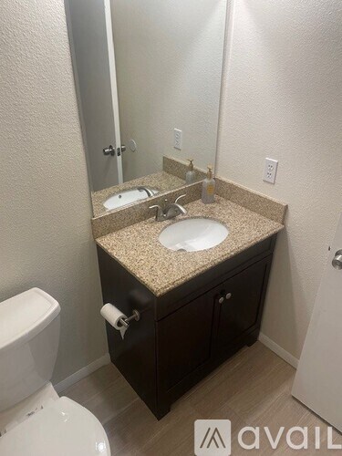 A bathroom with a toilet, sink, and mirror.
