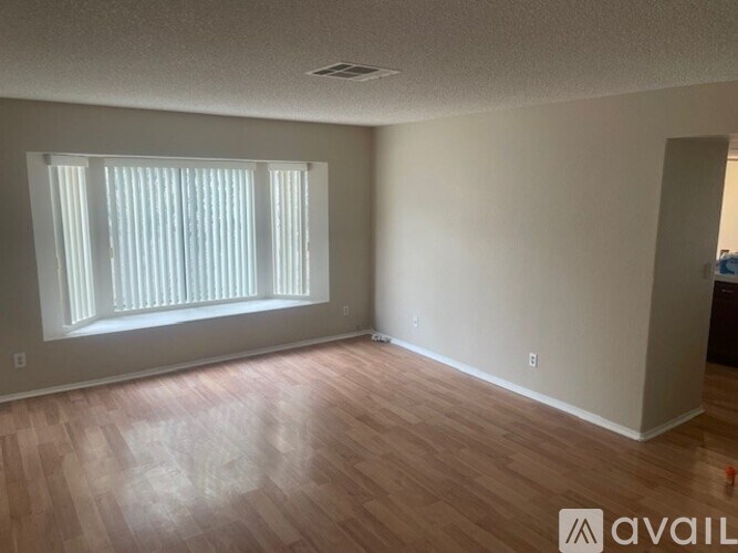 A room with wooden flooring and a window with blinds.
