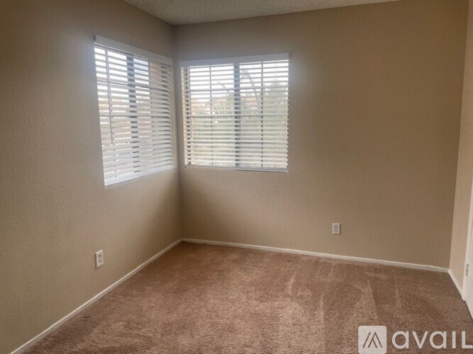 A room with carpeted floor and a window with blinds.
