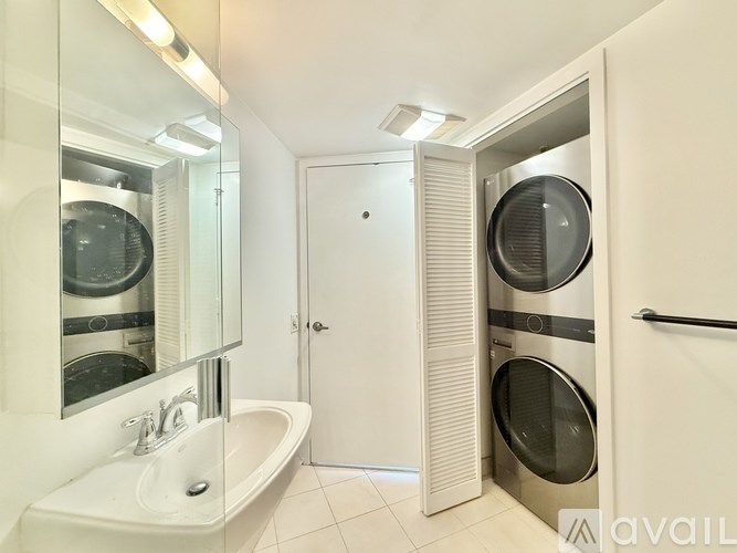 A bathroom with a white tub and a washer and dryer in the doorway.