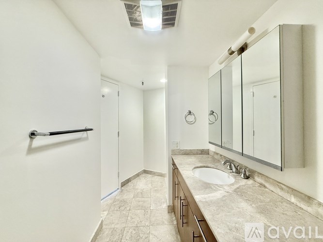 A bathroom with a sink, mirror, and towel rack.