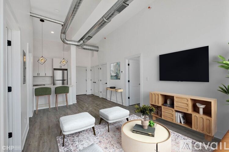 A modern living room with a white sofa, a grey rug, a wooden coffee table, and a black TV mounted on the wall.