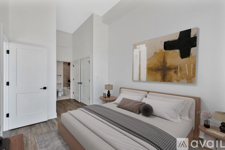 A bedroom with a large bed and a painting on the wall.