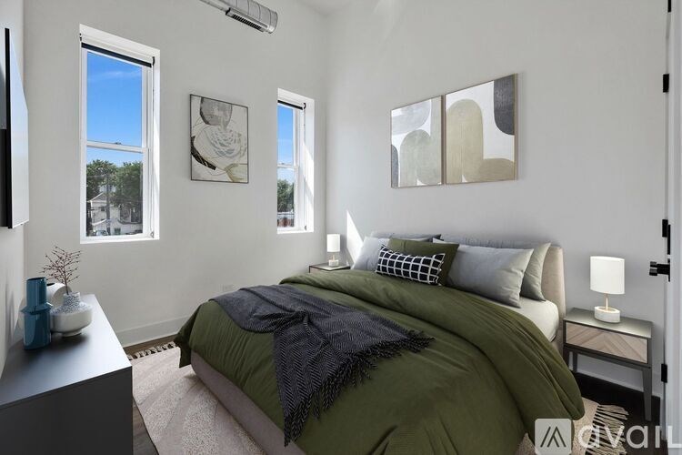 A bedroom with a bed covered in a green blanket and pillows.